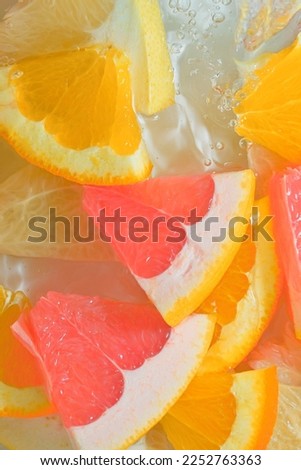Fresh slices of grapefruit, orange fruit and honey pomelo on white background. Pieces of grapefruit, orange fruit and honey pomelo in sparkling water on white background, close-up. Summer pattern.