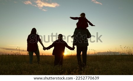 Parental care for children, Big family, group of people, nature. Active family with children walks in grass field in summer. Silhouette family, Dad mom daughter son go hand in hand outdoors in autumn.