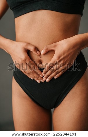  Close up off African American female making a heart shape with her hands on her tummy
