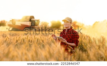 Woman farmer with digital tablet on a background of harvester. Smart farming concept. Royalty-Free Stock Photo #2252846547