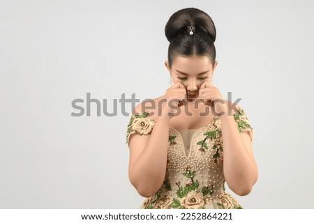 Portrait of beautiful Asian bride in luxurious wedding dress in thoughtful pose on white background, empty space for insert your advertisement