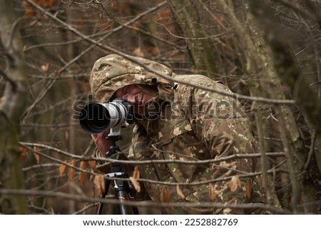 Professional wildlife photographer with camera in the wild Royalty-Free Stock Photo #2252882769