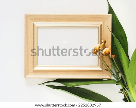 Beige rectangular picture frame and orange chrysanthemum blooming on white background. Flower frame isolated, flat lay with copy space.

