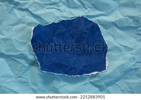 Blank torn paper isolated on blue background. Top view of crumpled blue paper piece with copy space.