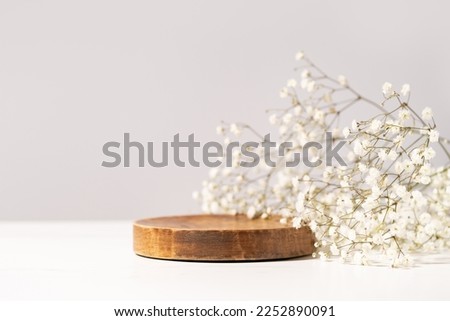 Beauty cosmetic product presentation scene made with a wooden plate and wild flowers. Summer mood background. Front view.