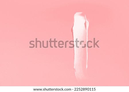 White cream smear on a pink background. High resolution photography.