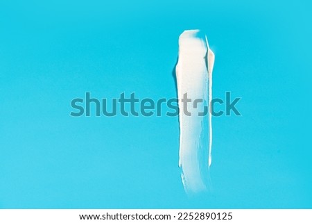White cream smear on a blue background. High resolution photography.