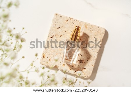 Summer fragrance concept made with perfume bottle on travertine plate in sunlight.