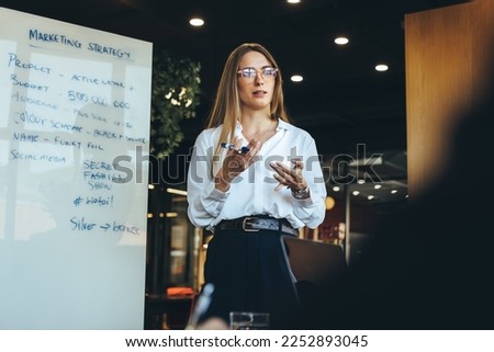 Female entrepreneur discussing her marketing strategy with her team in a modern workspace. Confident young businesswoman giving a presentation during a meeting with her colleagues. Royalty-Free Stock Photo #2252893045