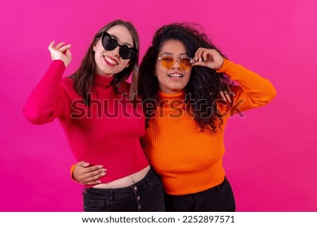 Female friends in sunglasses having fun and smiling on a pink background, studio shot, lifestyle