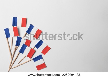 Small paper flags of France on light background, flat lay. Space for text