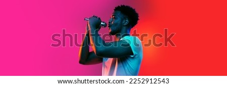 Singer. Horizontal banner with portrait of young african man over background in neon light. Beauty, fashion, youth and music concept. Copy space for ad, text