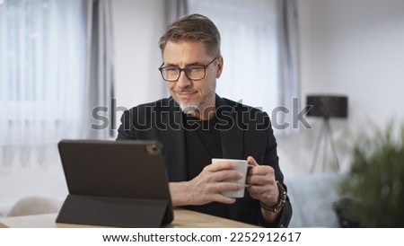 Businessman working with tablet computer in home office. Happy middle aged, mid adult, mature age man smiling. Entrepreneur sitting at desk, managing business online. Royalty-Free Stock Photo #2252912617