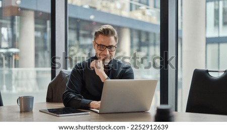 Business portrait - businessman using laptop computer in office, thinking. Happy middle aged man, entrepreneur working online. Royalty-Free Stock Photo #2252912639