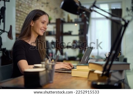 Businesswoman working with laptop computer in home office. Happy woman using the internet, searching, browsing, Blogger writing post online, smiling. Royalty-Free Stock Photo #2252915533