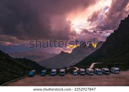 Motorhomes and campers parked in a rest caravan parking area in the Italian Alps on a mountain pass with a beautiful sunset. Traveling with a RV. Best option for summer tourism. Italy, Dolomites. Royalty-Free Stock Photo #2252927847