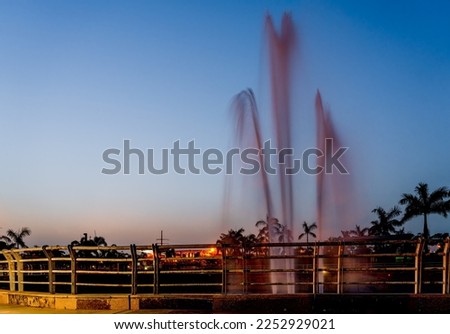 Long exposure of a fountain with railing and coconut tree gives a beautiful picture of nature after an amazing sunset and sky at Janeshwar Mishra Park in Gomti Nagar, Lucknow, Uttar Pradesh, India.