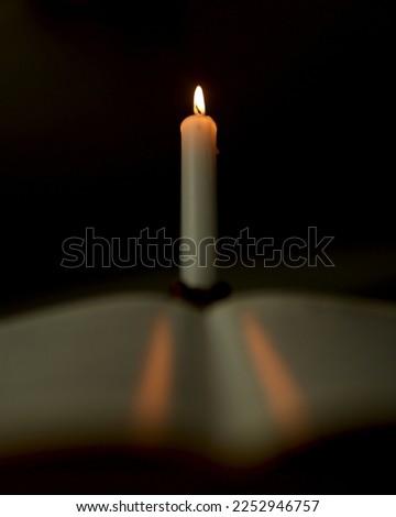 A candle and a book on the table. Bible for reading