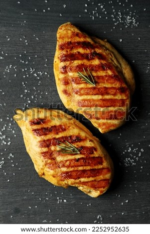 Grilled chicken meat and salt on dark wooden background