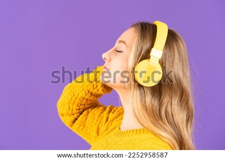 Closeup side view portrait of woman listening to music on headphones isolated on purple background