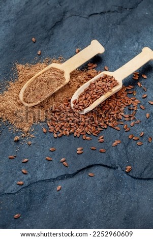 scoops of flax seeds and flax seed powder on black Royalty-Free Stock Photo #2252960609