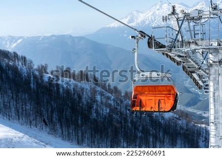 Empty bright orange ski chair lift in mountains in winter against the backdrop of snow Alpine skiing and snowboarding winter sports Royalty-Free Stock Photo #2252960691