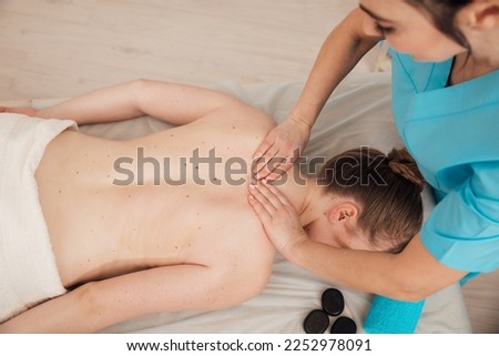 female masseur does spa therapeutic back massage with stones