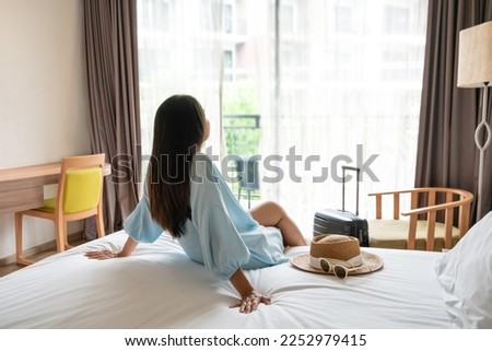 Carefree young Asian traveler woman relax on bed in hotel room. Travel alone, summer weekend concept. Royalty-Free Stock Photo #2252979415