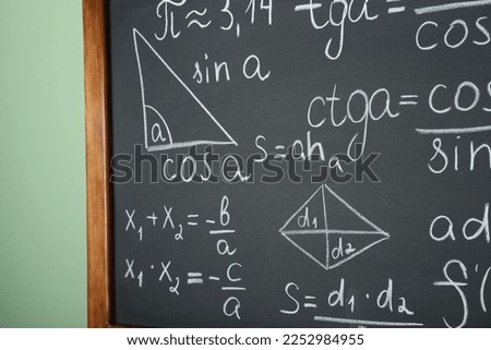 Chalkboard with many different math formulas on green wall, closeup