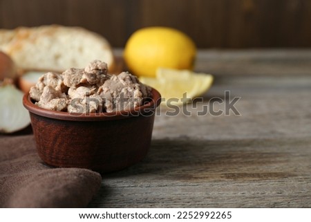 Bowl of tasty cod liver on wooden table, closeup. Space for text