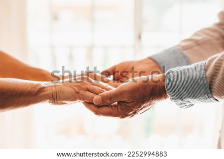 Close up elderly affectionate woman covering wrinkled hands of mature husband, showing love and support at home. Caring middle aged family couple enjoying sincere trustful honest conversation. Royalty-Free Stock Photo #2252994883
