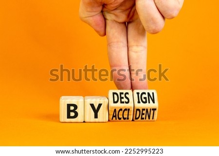 By accident and design symbol. Concept word By accident By design on wooden cubes. Beautiful orange table orange background. Businessman hand. Business by accident and design concept. Copy space.