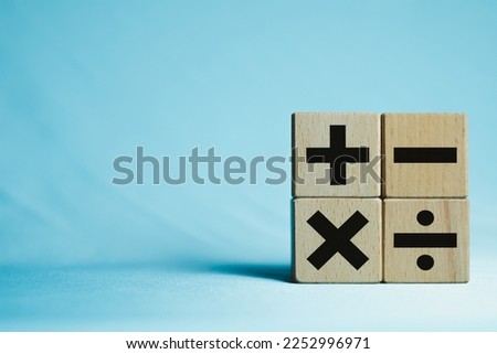 Image of wooden cubes displaying mathematical operation icons of Plus, minus, multiply and divide on a blue background with copyspace use for education,mathematic,symbol concept.