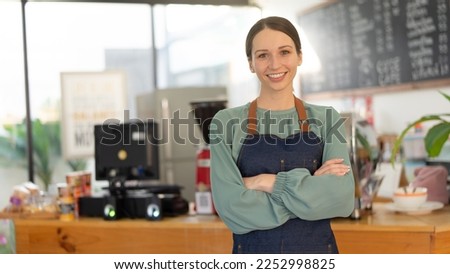 Portrait of happy waitress standing at restaurant entrance and holding digital tablet. 
