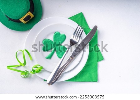 St. Patrick's Day festive table setting. Plate and cutlery with green napkin, shamrock symbol, gold horseshoe decor for luck. Patrick Day menu background, party invitation, top view copy space
