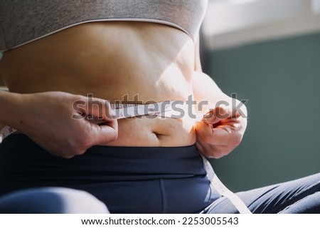 Beautiful fat woman with tape measure She uses her hand to squeeze the excess fat that is isolated on a white background. She wants to lose weight, the concept of surgery and break down fat under the Royalty-Free Stock Photo #2253005543
