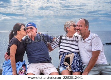 Happy couples embracing and kissing while enjoying vacation at sea looking at camera smiling.