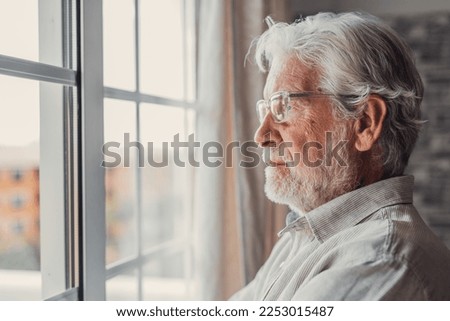 Pensive elderly mature senior man in eyeglasses looking in distance out of window, thinking of personal problems. Lost in thoughts elderly middle aged grandfather suffering from loneliness, copy space Royalty-Free Stock Photo #2253015487