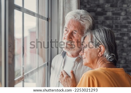 Pensive elderly mature senior man in eyeglasses looking in distance out of window, thinking of personal problems. Old woman wife consoling and hugging sad husband, copy space Royalty-Free Stock Photo #2253021293