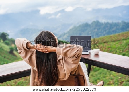 Young woman freelancer traveler working online using laptop and enjoying the beautiful nature landscape with mountain view Royalty-Free Stock Photo #2253022373