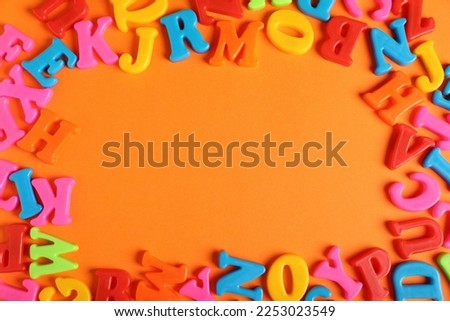 Frame made of many colorful magnetic letters on orange background, flat lay. Space for text