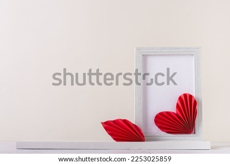 Blank photo frame decorated with DIY paper hearts. Home decor. Copy space
