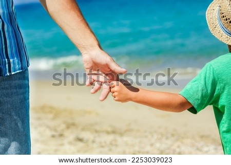 Hands of a happy parent and child on the seashore on a journey trip in nature