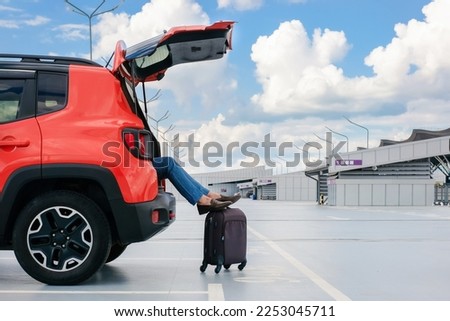 Car in the parking lot. Legs of a man peeking out of a car trunk on the street