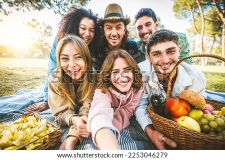 Group of friends taking selfie portrait picture with smartphone at the park - Happy young people having fun together hanging out on a sunny day - University students smiling at camera together