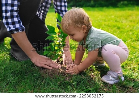 Father and his baby daughter planting tree together in garden, closeup Royalty-Free Stock Photo #2253052175