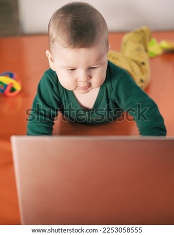Portrait of baby boy using a laptop computer at his business office - game room. Technology and toys concept. Funny babies
