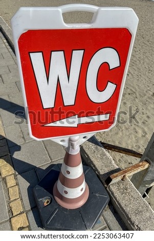 The sign of the simple design of the toilet indicates the direction to the WC on the beach