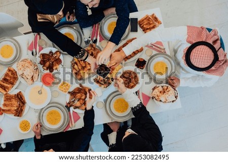  Muslim family having Iftar dinner drinking water to break feast. Eating traditional food during Ramadan feasting month at home. The Islamic Halal Eating and Drinking in modern home  Royalty-Free Stock Photo #2253082495