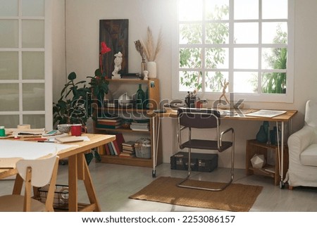 Part of living room in modern apartment serving as studio of art for freelance designer skilled in creating paintings and other items
